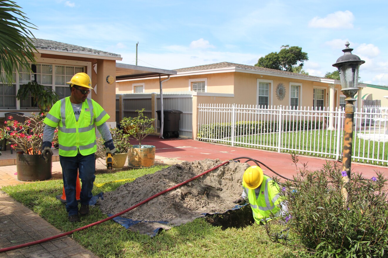 Florida Power and Light workers feed the PVC pipe that protects underground power lines under a yard on Bradley Court in West Palm Beach. They used directional boring to create a space for the power line without digging up the entire front yard. 